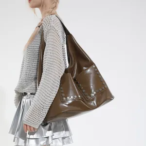 Deep brown oversized tote bag with silver rivets and polished finish on a female model