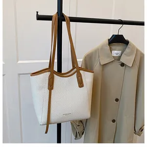 Close-up of woven tote bag with contrast brown leather straps and fashion text print
