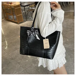 Détail du sac cabas noir à motif crocodile avec un foulard en soie à carreaux décoratif