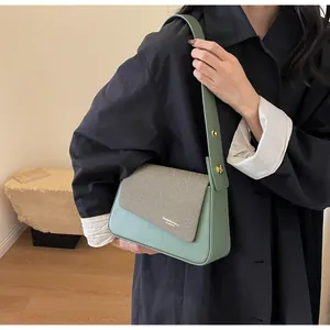 Détail du sac bandoulière en cuir vert menthe et tissu rayé gris avec boucles dorées