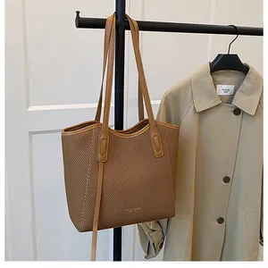 Close-up of brown tote bag with woven texture hanging next to a khaki trench coat