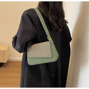 Détail du sac sous le bras en cuir vert avec rabat beige et boucle en métal doré