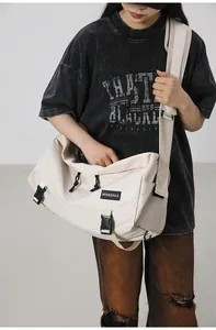 Dettaglio della borsa a tracolla in nylon beige con chiusura a fibbia e coulisse