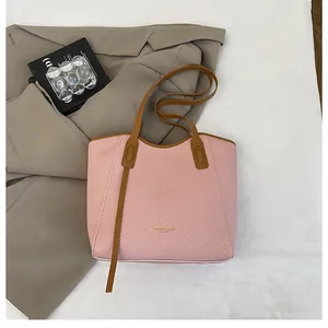 Detailed top view of a pink woven tote bag with brown leather trim and stylish accessories