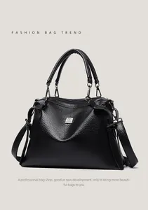 Close-up of black lychee texture leather handbag with circular handles and metal logo