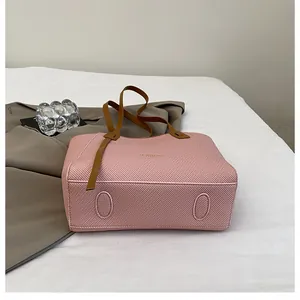 Close-up of pink tote bag with textured surface and reinforced brown bottom details