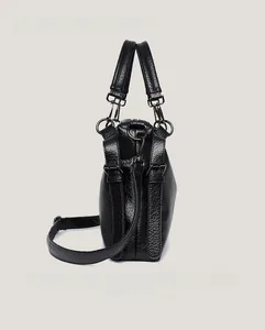 Detail of black pebbled leather texture on tote bag with wide strap and gunmetal hardware