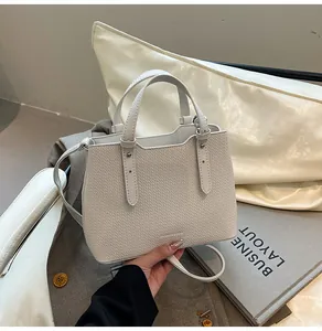 Dettaglio borsa tote color crema testurizzata con manici cilindrici e tracolla regolabile