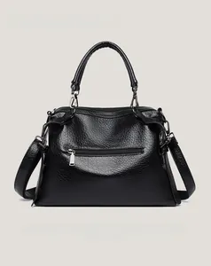 Detail of black litchi pattern faux leather handbag with metal buckle and zipper pocket