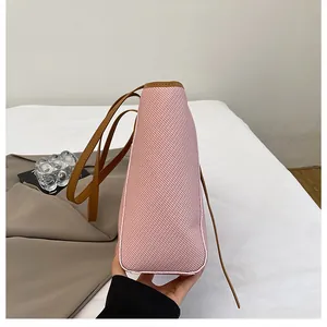 Detail view of pink tote bag showing woven texture and brown contrast strap