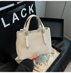 Dettaglio borsa a mano intrecciata color crema con manico e inserti in metallo