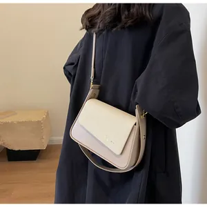 Détail du sac à bandoulière en cuir beige et tissu avec rivet doré et bandoulière réglable