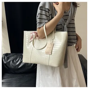 Détail du sac cabas blanc à motif crocodile avec un foulard en soie rose sur l'anse