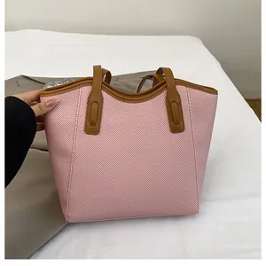 Detail of pink tote bag with brown straps showing durable woven fabric texture and size