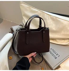 Dettaglio della borsa tote in pelle marrone scuro con bordo ondulato e rivetti argento