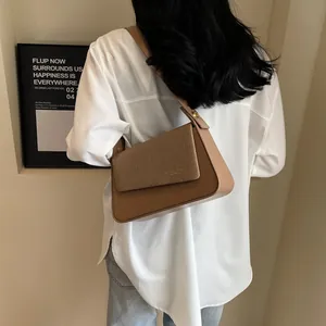 Sac bandoulière minimaliste marron en cuir lisse et texture tissée porté en travers