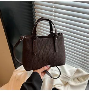 Dettaglio della pelle intrecciata marrone scuro e finiture in metallo della borsa