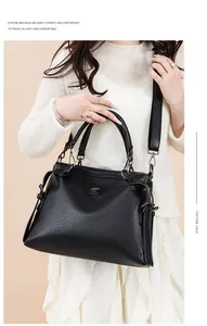 Detail of black pebbled leather tote bag with metallic logo plate and side strap accents