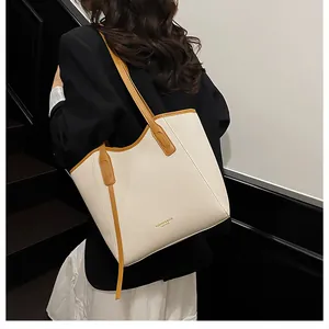 Detail of a large tote bag featuring beige woven texture and brown leather trim accents