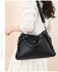 Close-up of black lychee grain leather tote bag with metallic logo and adjustable strap