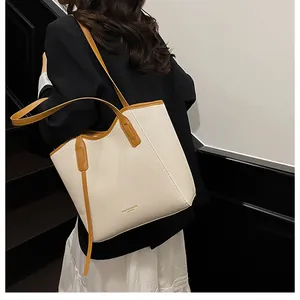 Detail of a large cream canvas tote bag with brown leather straps shown on a model
