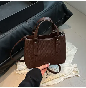 Dettaglio borsa tote in pelle marrone con manici robusti e hardware in metallo argento