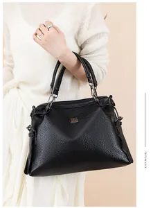 Close-up of black leather handbag featuring lychee texture and square metal logo detail
