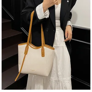 Close-up of a stylish woven tote bag with brown leather handles and fashion lettering