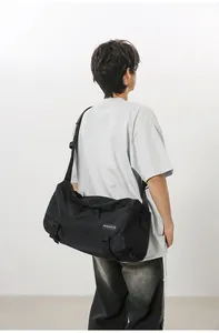 Dettaglio della grande borsa a tracolla nera con materiale in nylon ed etichetta tessuta