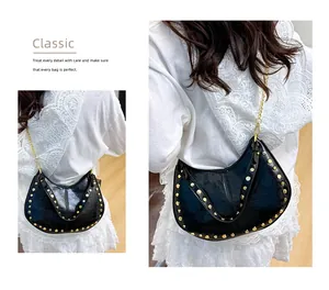 Détail d'un sac hobo noir à rivets dorés avec une bandoulière en chaîne fine