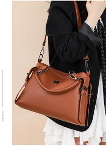Detail of brown pebbled leather crossbody bag with silver hardware and detachable strap