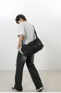 Vista laterale della borsa a tracolla grande in nylon nero con fibbia su un modello