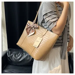 Gros plan de la texture crocodile sur un sac fourre-tout beige avec foulard décoratif