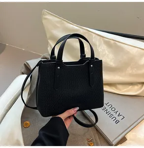 Dettaglio macro della trama intrecciata nera su una borsa tote in pelle con rivetti argento