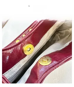 Détail macro du fermoir magnétique doré sur un sac à main en cuir bordeaux