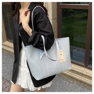 Détail d'un sac cabas bleu clair à motif crocodile avec un foulard en soie fleurie