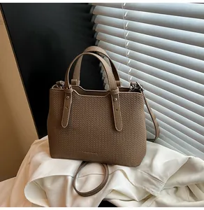 Dettaglio della borsa tote tortora con trama intrecciata e rivetti in argento