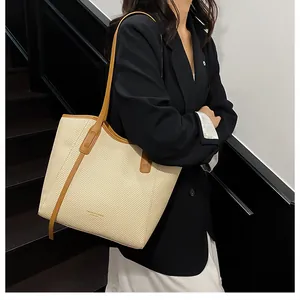 Detail of large woven tote bag with brown leather handles and contrast trim accents
