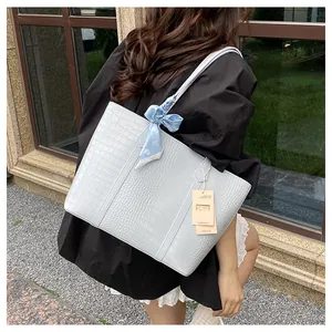 Détail d'un sac cabas bleu clair embossé crocodile avec foulard fleuri et étiquette