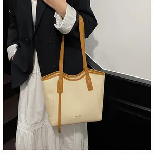 Detail of minimalist woven tote bag with brown leather trim worn by model in suit