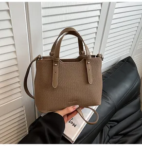 Dettaglio della trama intrecciata della borsa tote marrone con rivetti e tracolla rimovibile