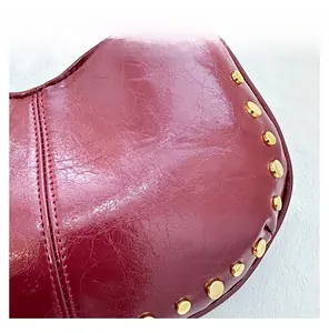 Détails du sac à bandoulière en cuir verni bordeaux avec rivets dorés polis