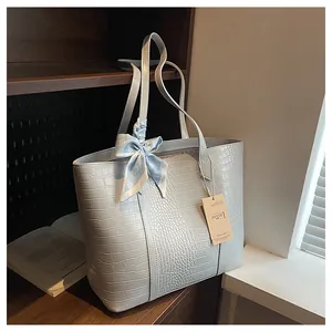 Détail du sac cabas bleu clair à motif crocodile avec un foulard en soie décoratif