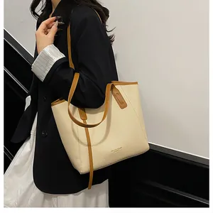 Detail of large cream tote bag with woven texture and brown leather shoulder straps