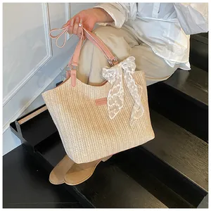 Close-up of straw tote bag showing woven texture and pink leather handle with lace bow