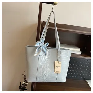 Détail du sac cabas bleu clair à texture crocodile avec foulard en soie élégant