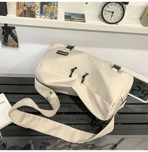 Dettaglio della borsa a tracolla beige minimalista con cinghie a fibbia su una sedia