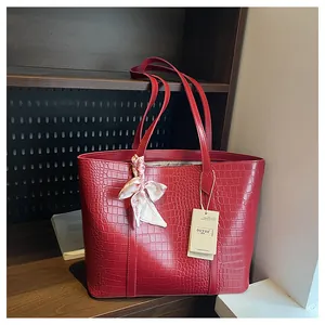 Vue détaillée du sac cabas rouge à motif crocodile avec foulard floral sur l'anse