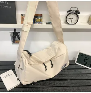 Dettaglio borsa a tracolla crema con tiretti neri su una scrivania in stile minimal