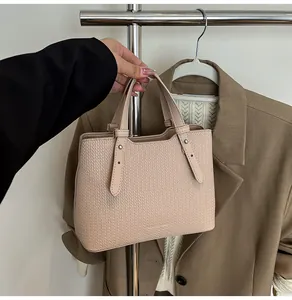 Vista dettagliata della borsa tote beige in pelle goffrata con rivetti metallici argentati